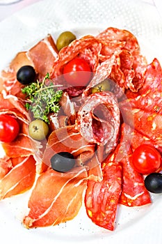 Italian salumi meat platter - prosciutto ham, salami olive and cherry tomato.