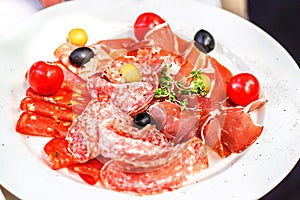 Italian salumi meat platter - prosciutto ham, salami olive and cherry tomato. photo