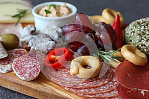 Italian sausages sliced on a meat board with pate, pepper and traditional taralli biscuits - the concept of a snack for red wine
