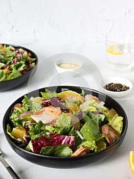 Italian shrimp salad with oranges, red onions, green lettuce, olive oil and sesame seeds.