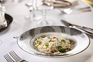 Italian Spaghetti Algio e Olio with Garlic Parmesan and chili peppers on restaurant festive table