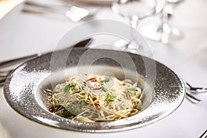 Italian Spaghetti Algio e Olio with Garlic Parmesan and chili peppers on restaurant festive table