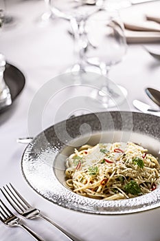 Italian Spaghetti Algio e Olio with Garlic Parmesan and chili peppers on restaurant festive table