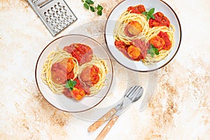 Italian spaghetti pasta with meat balls and tomato sauce served with oregano in two bowls on a light marble table. Top view, copy