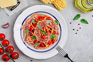 Italian spaghetti pasta with tomato sauce, basil and parmesan cheese on gray stone background. View from above