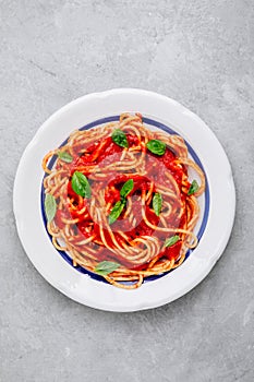 Italian spaghetti pasta with tomato sauce, basil and parmesan cheese on gray stone background. View from above