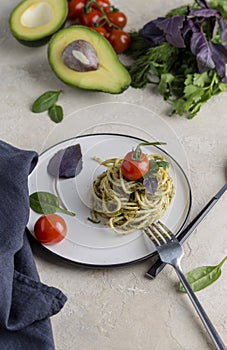 Italian spaghetti with pesto, herbs and cherry tomatoes at white plate