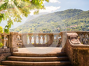 Italian stone balustrade illuminated by sun rays and water in the background photo