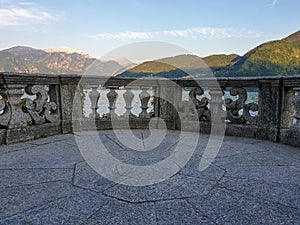 Italian stone balustrade illuminated by sun rays and water in the background photo