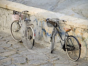 Italian street scene. Two bikes parked by stone wall