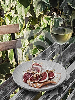 Italian style aperitif - bruschetta with cheese, figs, honey, nuts and a glass of white wine on a table in an outdoor cafe