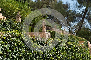 Italian style Mediterranean garden. tone statues surrounded by vegetation. Mallorca, Spain.