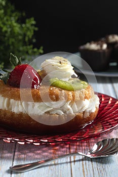 Italian sweet with rum syrup with strawberries, kiwi, pineapple slice and whipped cream