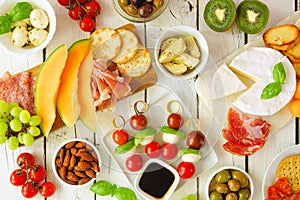 Italian theme grazing table scene against a white wood background. Overhead view.