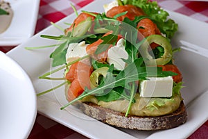 Italian traditional bruschetta with tomato basil and green olives. Served on a white plate over red plaid tablecloth.