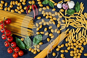 Italian traditional food, spices and ingredients for cooking as basil leaves, cherry tomatoes, chili pepper, garlic, various pasta