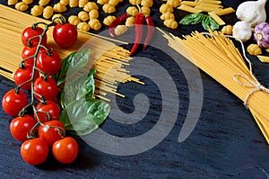 Italian traditional food, spices and ingredients for cooking: basil leaves, cherry tomatoes, garlic, chili pepper, pasta