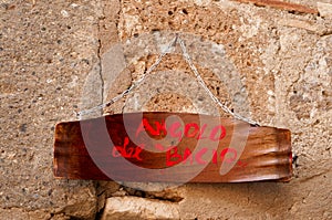 Italian vintage wood  signboard hanging on a tufa wall. translation: