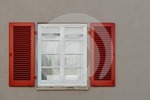 Italian windows on the grey wall facade with open red color classic shutters. window shutter wall europe