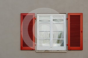 Italian windows on the grey wall facade with open red color classic shutters. window shutter wall europe