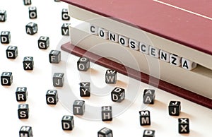 Italian word conoscenza meaning knowledge written with letters trapped between a book files and spread letters on white background photo