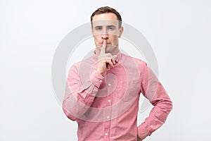 Italian young man in pink shirt doing a silence gesture