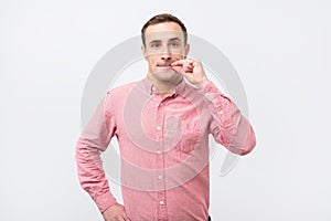 Italian young man in pink shirt doing a silence gesture