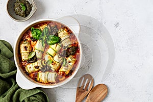 Italian zucchini rolls with cream cheese filling, baked in tomato sauce on a white background.