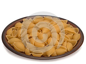 Italy dry raw pasta conchiglie on the plate. Closeup on white background