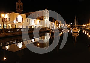 Italy. Emilia-romagna. Cesenatico. Canal of night town on black sky background, horizontal view.