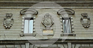 Italy, Milan, Via Farine, two windows and three blazons on the facade of the building