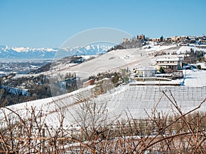 Italy Piedmont: Barolo wine yards unique landscape winter, Novello medieval village castle on hill top, the Alps snow capped