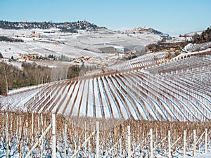 Italy Piedmont: row of wine yards, unique landscape in winter with snow, rural village on hill top, italian historical heritage