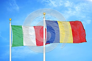 Italy and Romania two flags on flagpoles and blue cloudy sky