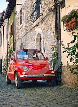 Italy. A tiny red vintage Italian car parked in an Italian town area