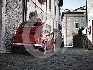 Italy. A tiny red vintage Italian car parked in an Italian town area