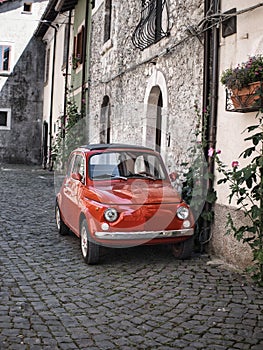 Italy. A tiny red vintage Italian Fiat car parked in an Italian town area