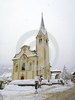 Italy, Trentino Alto Adige, Bolzano, San Vigilio di Marebbe, view of the church of the town during a winter day and during a snowf photo