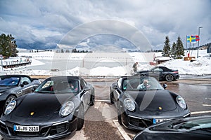 Italy, Trentino, 29 April 2019: The group of luxury sports cars does a stop on the twisting road, snow-covered field on