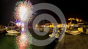 Italy, Tuscany Maremma Castiglione della Pescaia, fireworks over the sea, panoramic night view of the port and the castle