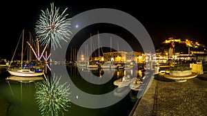 Italy, Tuscany Maremma Castiglione della Pescaia, fireworks over the sea, panoramic night view of the port and the castle