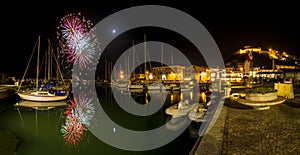 Italy, Tuscany Maremma Castiglione della Pescaia, fireworks over the sea, panoramic night view of the port and the castle
