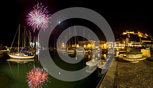 Italy, Tuscany Maremma Castiglione della Pescaia, fireworks over the sea, panoramic night view of the port and the castle