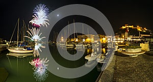 Italy, Tuscany Maremma Castiglione della Pescaia, fireworks over the sea, panoramic night view of the port and the castle