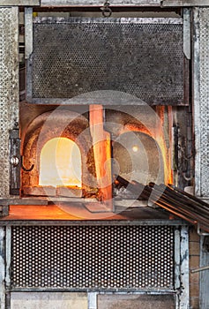 Italy, Venice, Murano glass factory special glass-blowing tools: red-hot furnace with fire to make the glass malleable, and iron