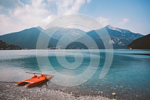 Italy view of a mountain lake lago di ledro with a beach and a lifeboat catamaran of red color in summer in cloudy weather