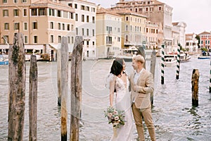 Italy wedding in Venice. The bride and groom are standing on a wooden pier for boats and gondolas, near the Striped