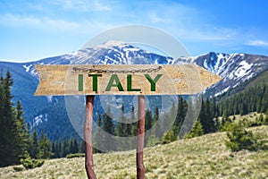 Italy wooden arrow road sign against mountains landscape