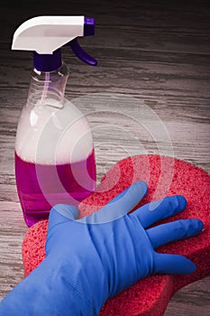 Items for cleaning, a hand in a blue glove holding a red sponge