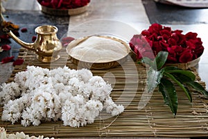 Items for the Indian Yajna ritual. garland of white flowers, red rose petals and copper dish with rice for Hindu Vedic Yajna